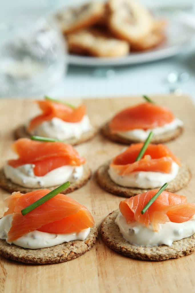 Canapé with cream and smoked salmon on a wooden board.